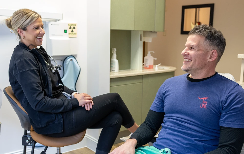 Dental assistant having friendly conversation with patient during painless dental cleaning appointment at Creedmoor Road