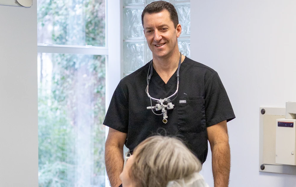 Dr. Lee Allen smiling and discussing dentures and full arch implants options with patient at Creedmoor Road