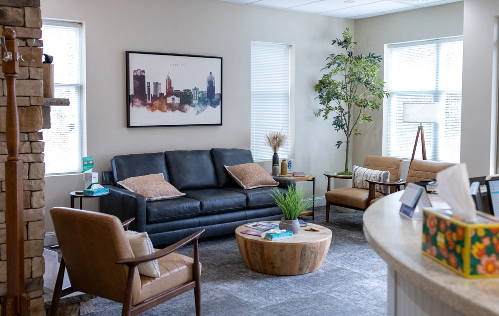 Comfortable waiting room with sofa and chairs in creedmoor road dental office
